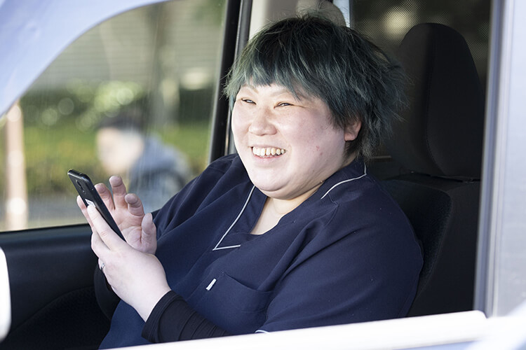 車内でスマホアプリから業務報告をする介護士